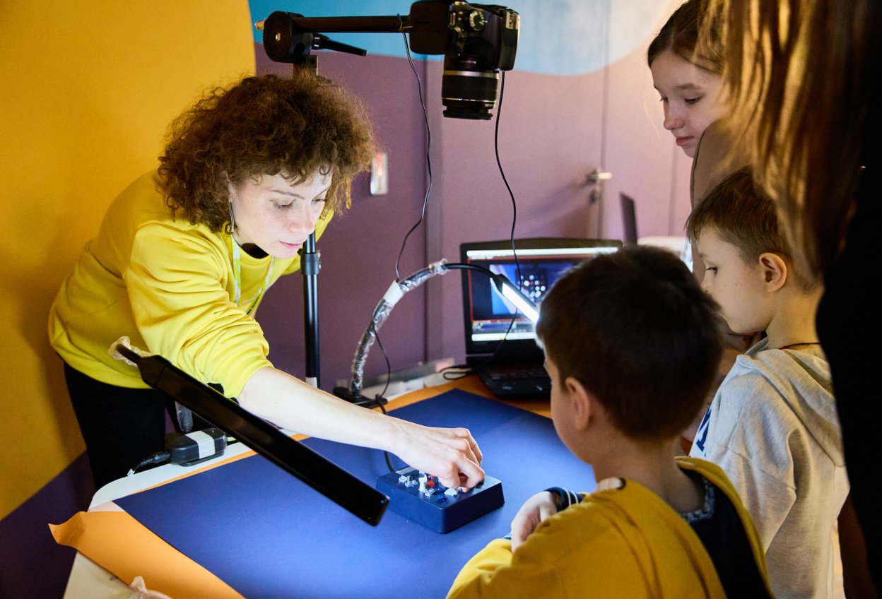 Девушка показывает детям, как работает конструктор