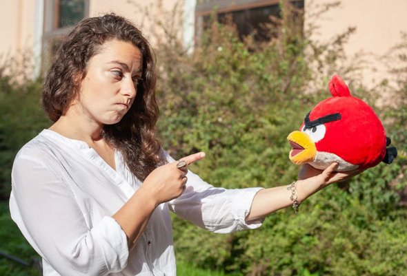 Девушка держит в руках и указывает пальцем на мягкую игрушку Angry Birds. Подростковый мат