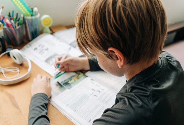 Подросток делает домашку дома за столом