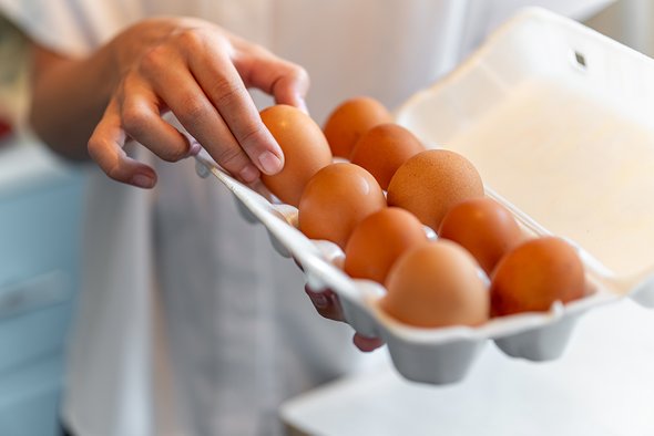 Упаковка яиц. Рука достает яйцо из упаковки