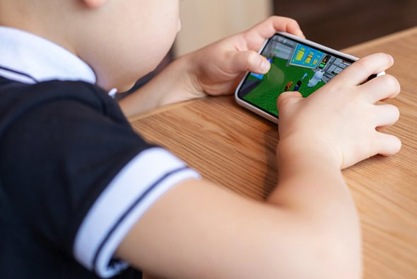 Ребенок играет на смартфоне в Roblox