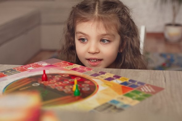 Девочка-ребенок играет в настольную игру. Развитие речи