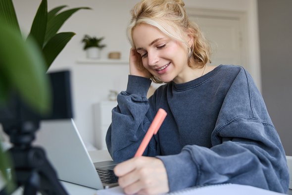 Девушка сидит за ноутбуком и пишет ручкой. Проджект-менеджер. 5 IT-направлений для ребенка, который не дружит с математикой