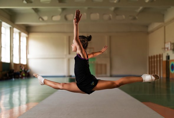 Девочка ребенок на тренировке по гимнастике в спортивном зале