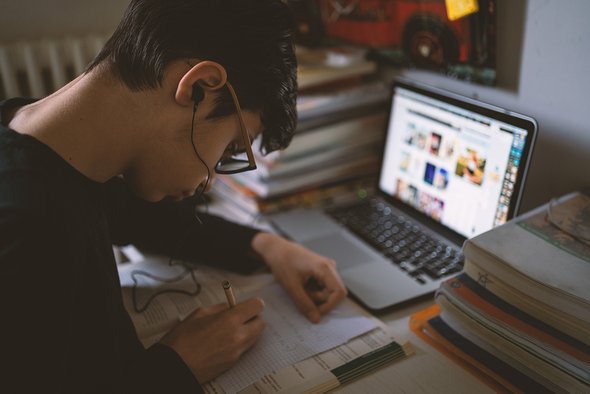 Подросток делает домашнее задание с ноутбуком