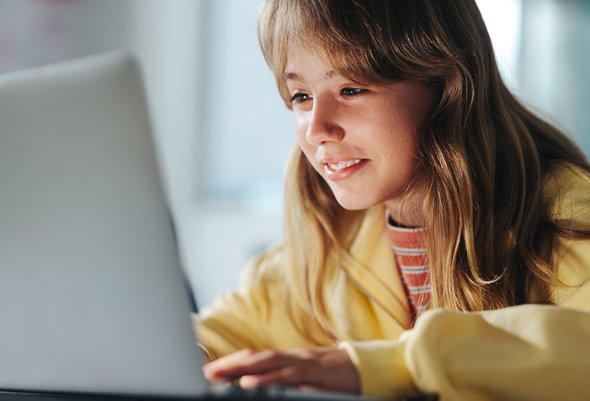 Радостная девочка подросток сидит за ноутбуком. 5 IT-направлений для ребенка, который не дружит с математикой