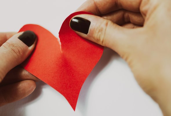 Женские руки рвут сердечко из бумаги