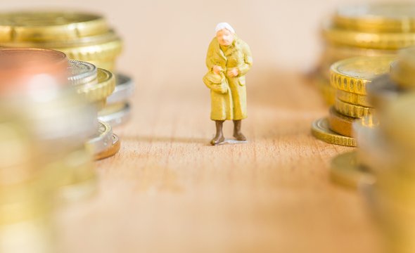 Пенсии в 2026 году. Миниатюрная фигурка старушки рядом с монетами