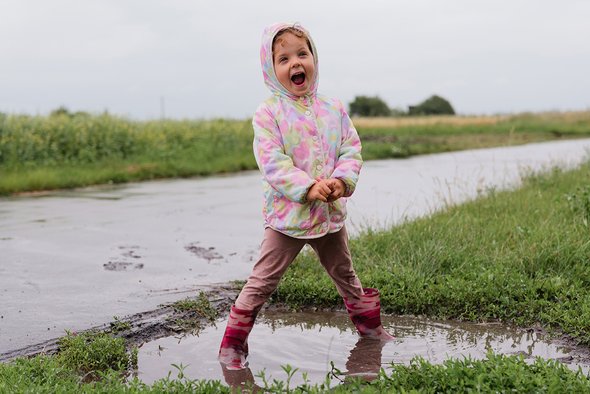 Девочка-ребенок гуляет и стоит в луже