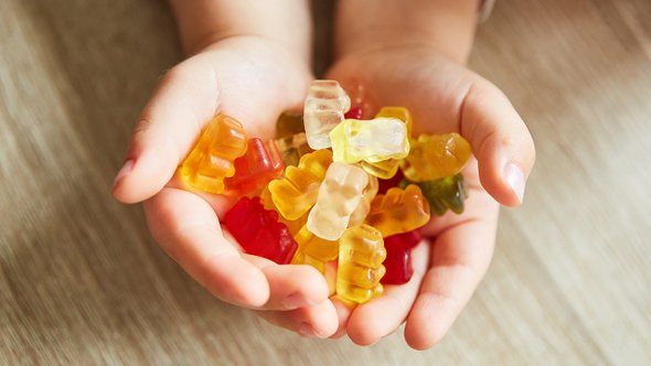 Ребенок держит в руках много мармеладных мишек