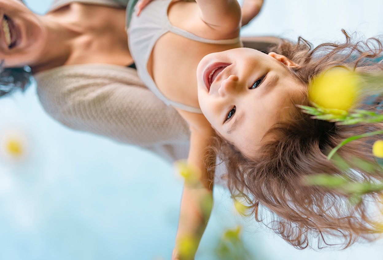 Мама держит ребенка на руках вверх ногами. Няня