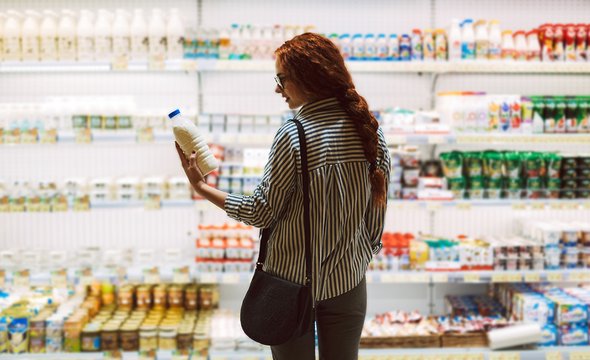 Девушка в супермаркете держит бутылку с молоком