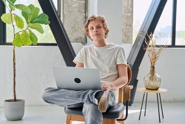 Молодой парень сидит на стуле с ноутбуком. Тестировщик. 5 IT-направлений для ребенка, который не дружит с математикой