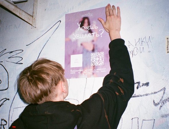 Александр Сапрыкин расклеивает плакаты со своими рисунками для бренда SRNK