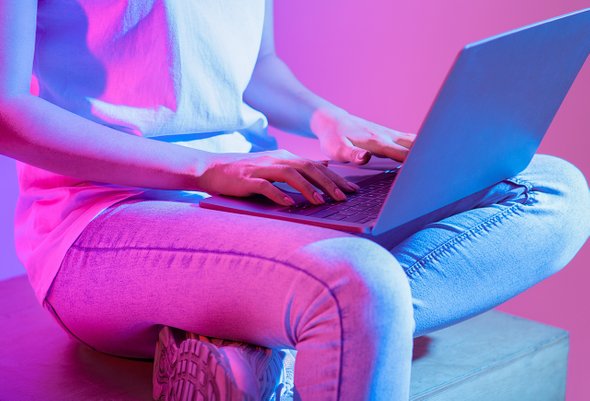 Девушка сидит с ноутбуком в неоновым свете. Конструкторы резюме