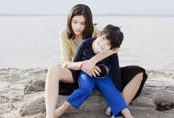 Сестра сидит на пляже с братом, больным ДЦП. Как живут братья и сестры тяжелобольных детей